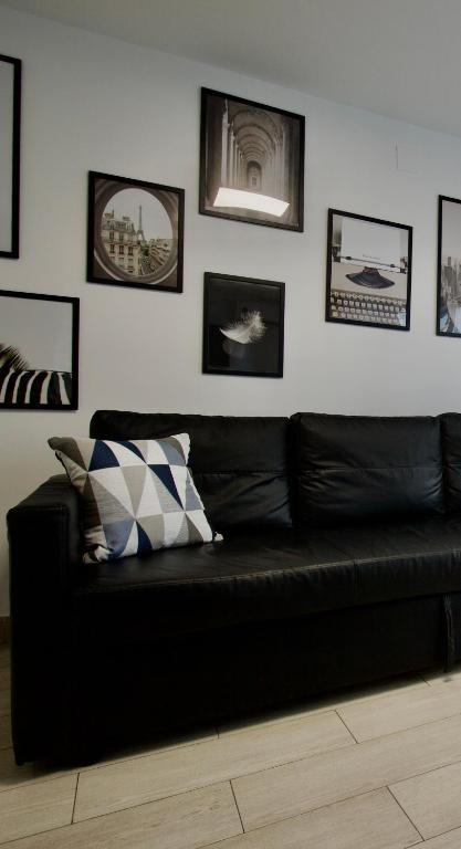 a black couch in a room with pictures on the wall at Vanili Santa Pola in Santa Pola
