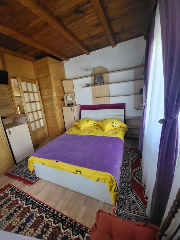 a bedroom with a bed with purple and yellow sheets at Casa Roza in Breaza de Sus