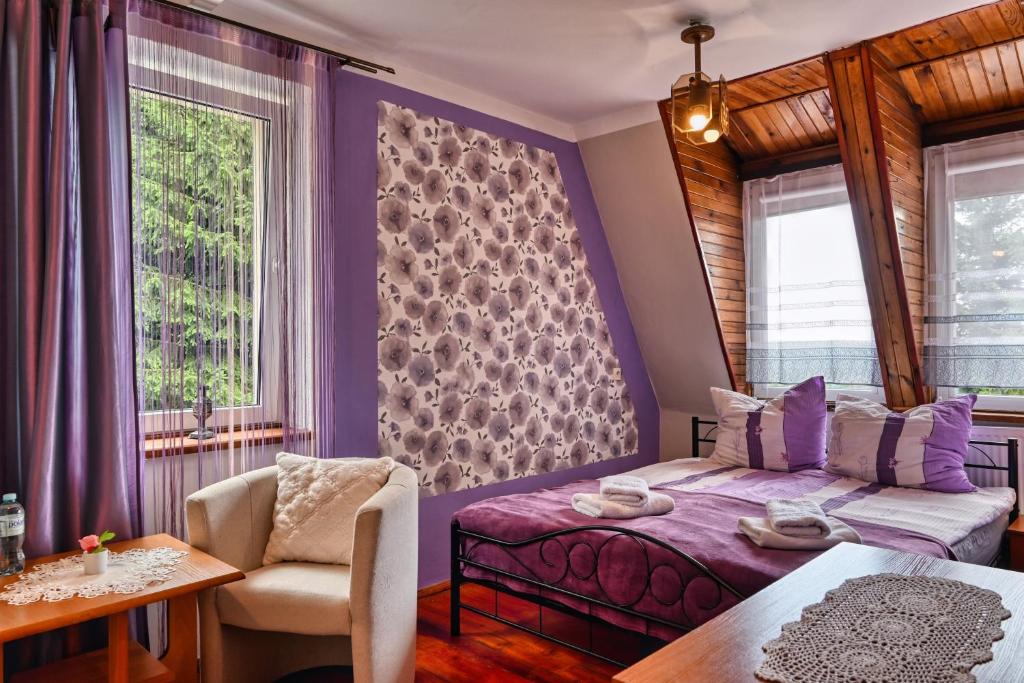 a bedroom with purple walls and a bed and a table at Zbójnicka Chata in Duszniki Zdrój