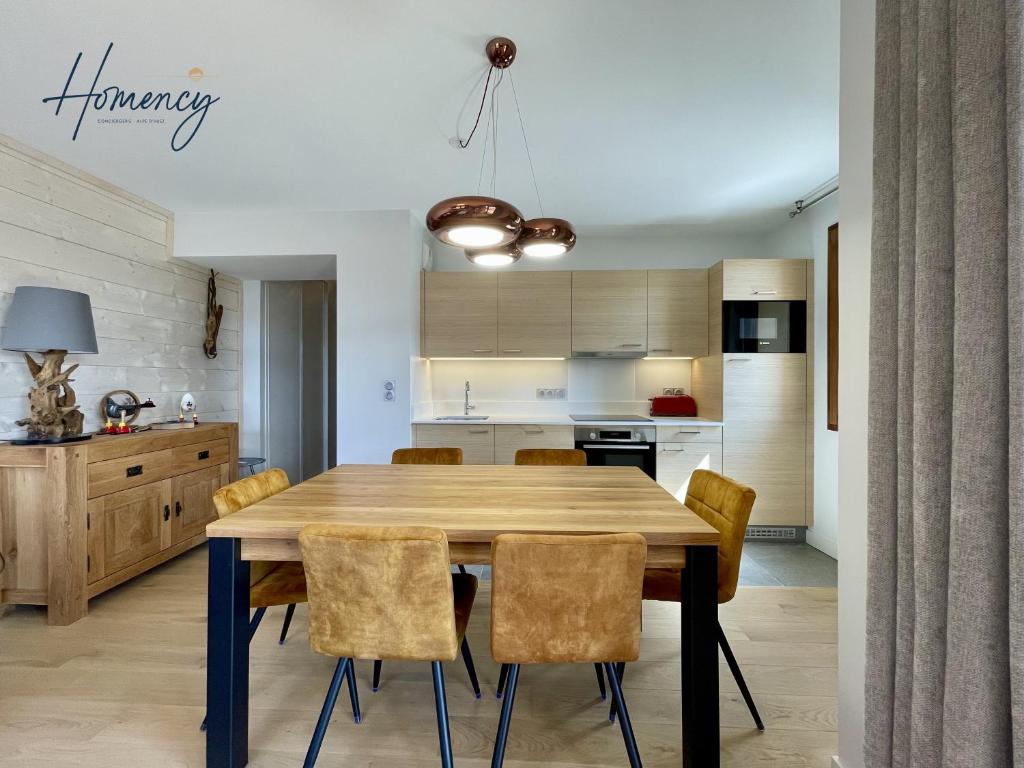 une cuisine et une salle à manger avec une table et des chaises en bois dans l'établissement Homency - Résidence Fermes de l'Alpe A102, à L'Alpe-d'Huez