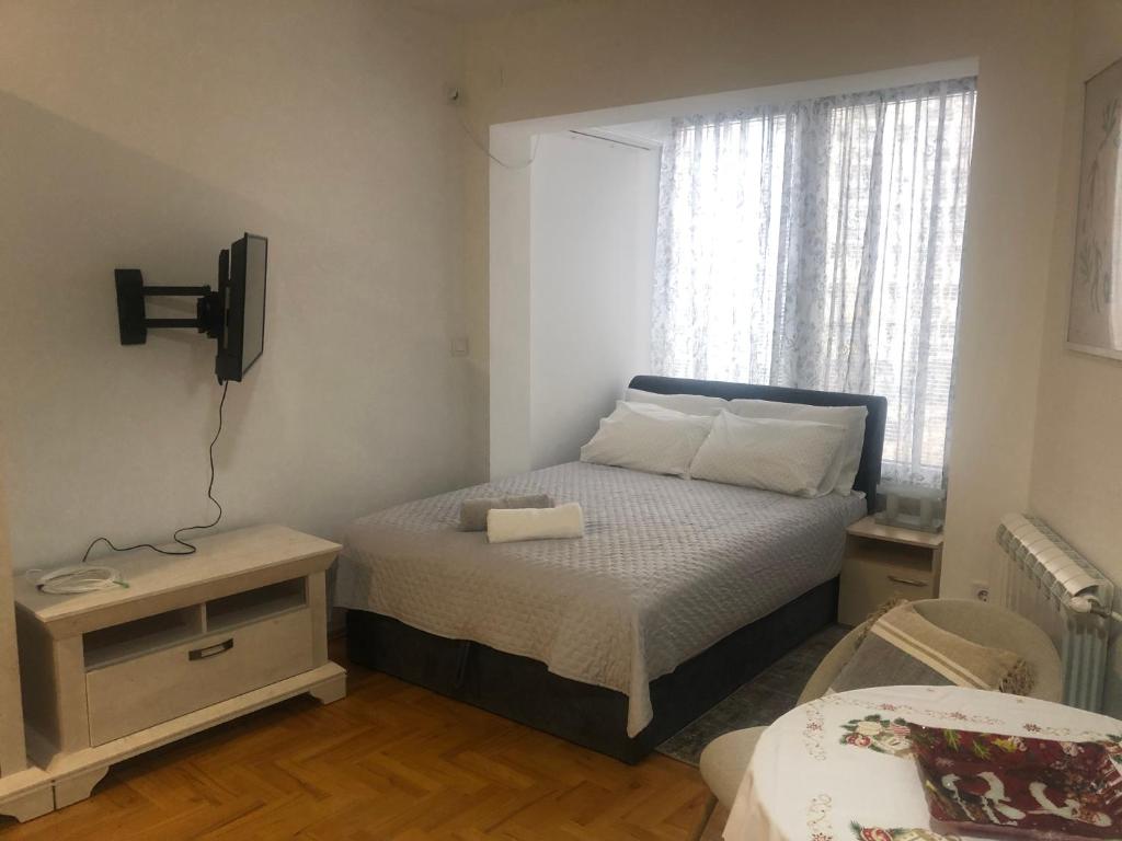 una piccola camera da letto con un letto e una finestra di Snow white studio a Skopje