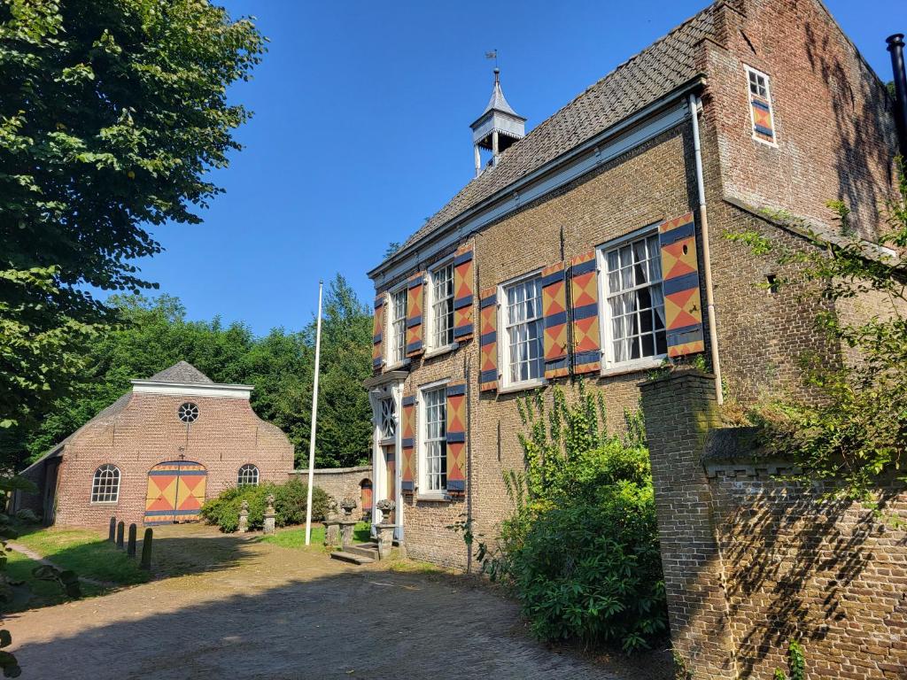 an old brick building with mosaicked windows and a church at Zuidewijn in Sprang-Capelle