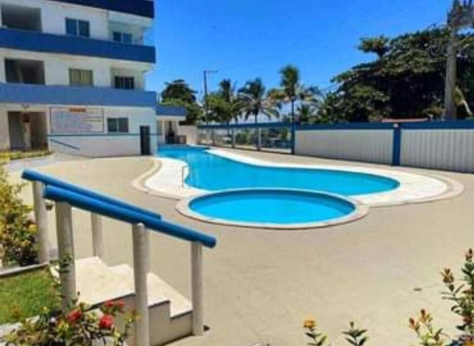 una piscina con acqua blu di fronte a un edificio di Apt 202 Frente para o Mar e Piscina Village das Ondas a Piúma