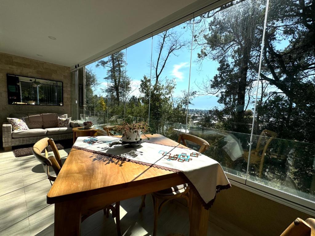 a dining room with a table and a large window at Hermoso Entorno y Vista Espectacular en Pucon in Pucón