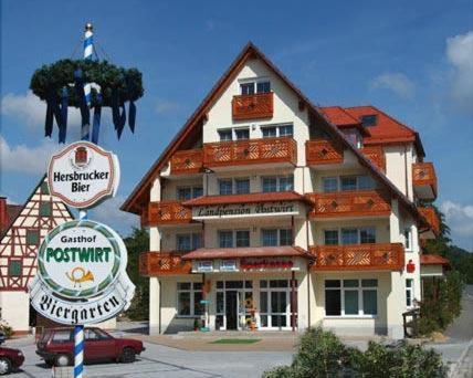 een groot gebouw met een bord ervoor bij Hotel-Landpension Postwirt in Kirchensittenbach