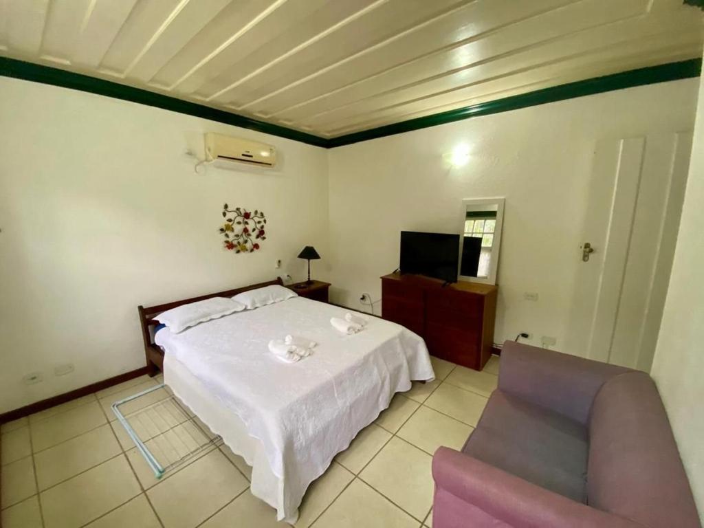 a bedroom with a bed and a chair and a television at Fantastica casa no melhor condomínio de Paraty in Paraty