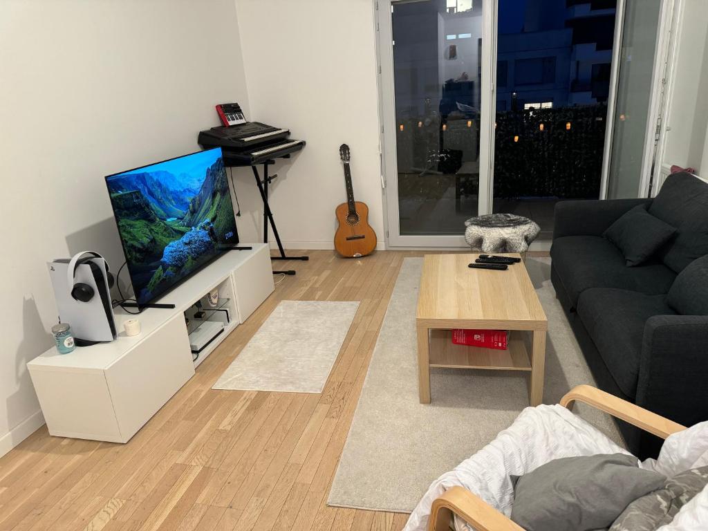 un salon avec un canapé et une télévision à écran plat dans l'établissement Splendide appartement type T2, à Villejuif