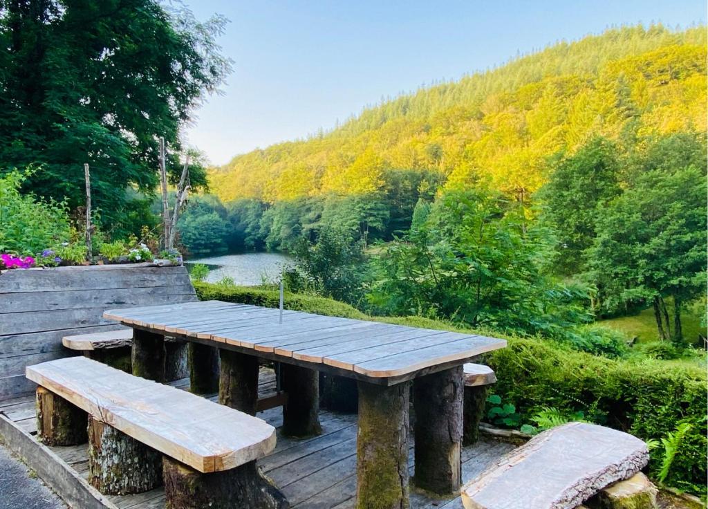 a wooden picnic table with two benches and a river at MAGNIFIQUE Location au bout de la route in Saint-Hilaire-les-Courbes
