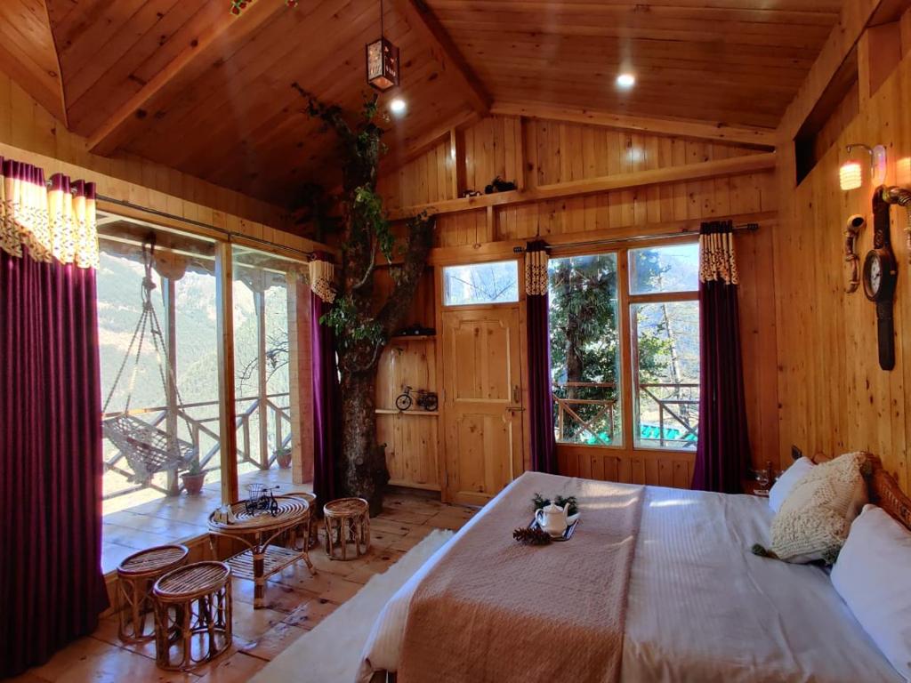 a bedroom with a large bed in a room with wooden walls at Hunting Wood Tree Cottage Seri in Jibhi