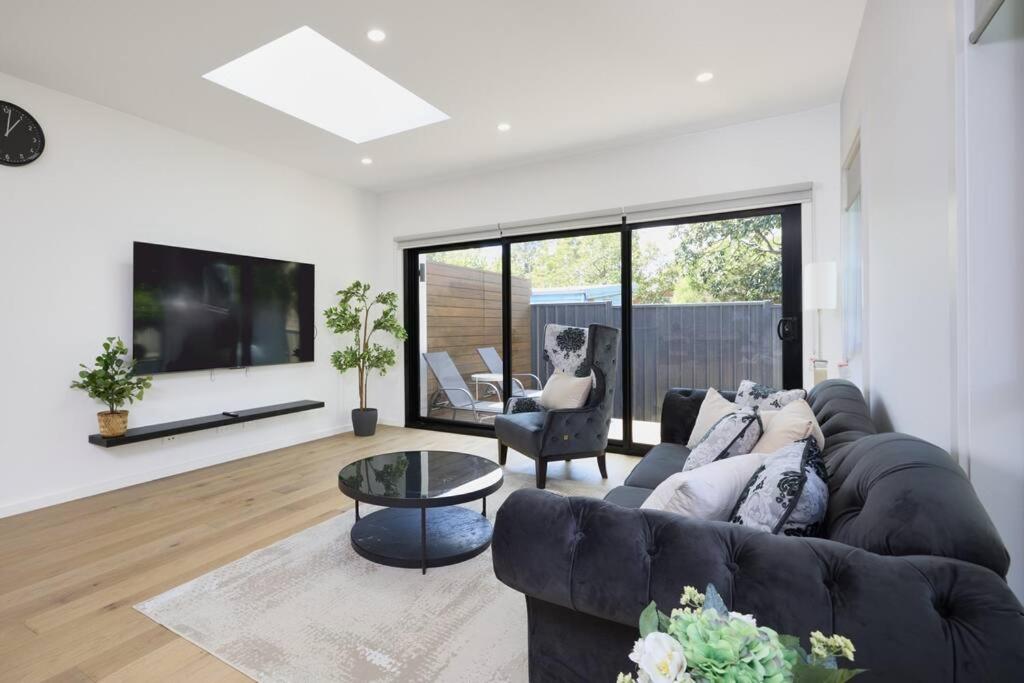 a living room with a black couch and a tv at Preston Lux House 5 bed 5 bath in Melbourne