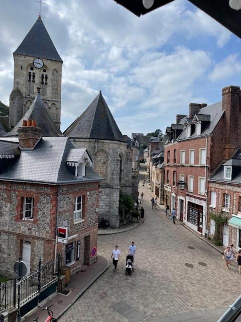 un groupe de personnes marchant dans une rue avec une tour d'horloge dans l'établissement Le fournil, à Veules-les-Roses