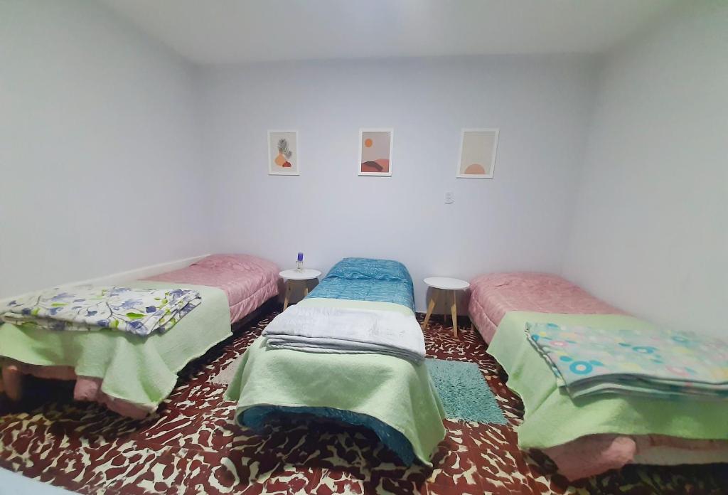 une chambre avec trois lits avec des couvertures dessus dans l'établissement Casa Centrica 2 habitaciones con Cochera SL Cap, à San Luis