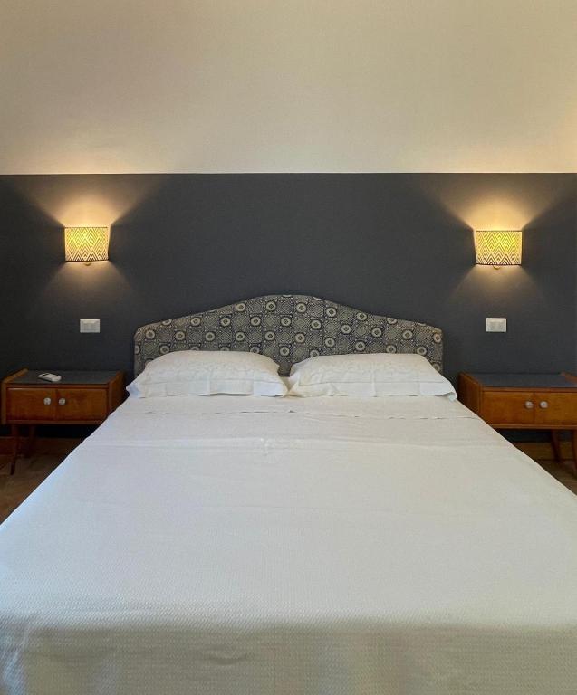 una camera da letto con un grande letto bianco con due comodini di La Pausa a Portoferraio