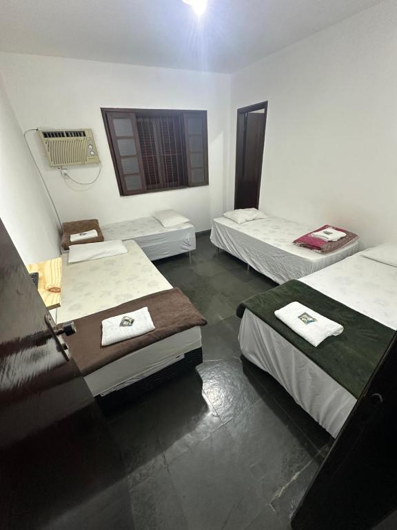 a room with three beds and a window at Pousada e Restaurante Dona Lu in Itaperuna