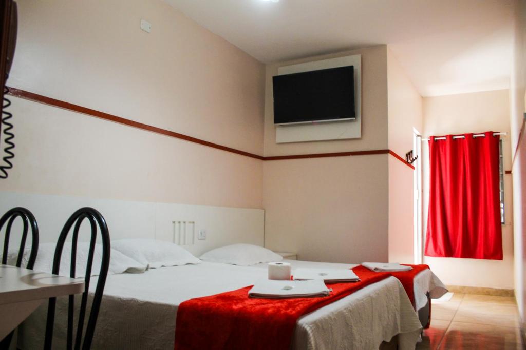 Una habitación de hotel con una cama y un televisor en la pared. en Hotel Itaquera, en São Paulo