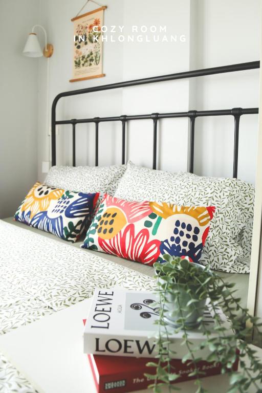 a bed with two pillows and a book on it at Cozy room in Khlongluang II - Self Check-in in Khlong Luang
