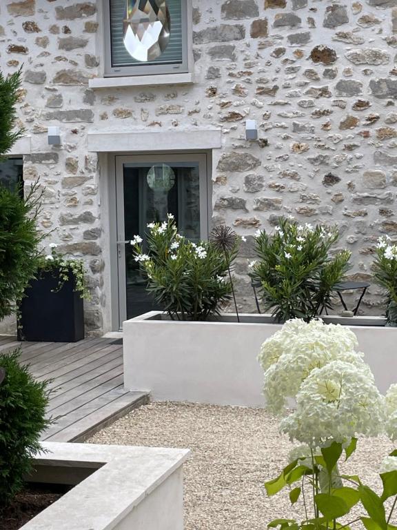 a stone building with a door and some plants at Le Passage Secret in Fleury-en-Bière