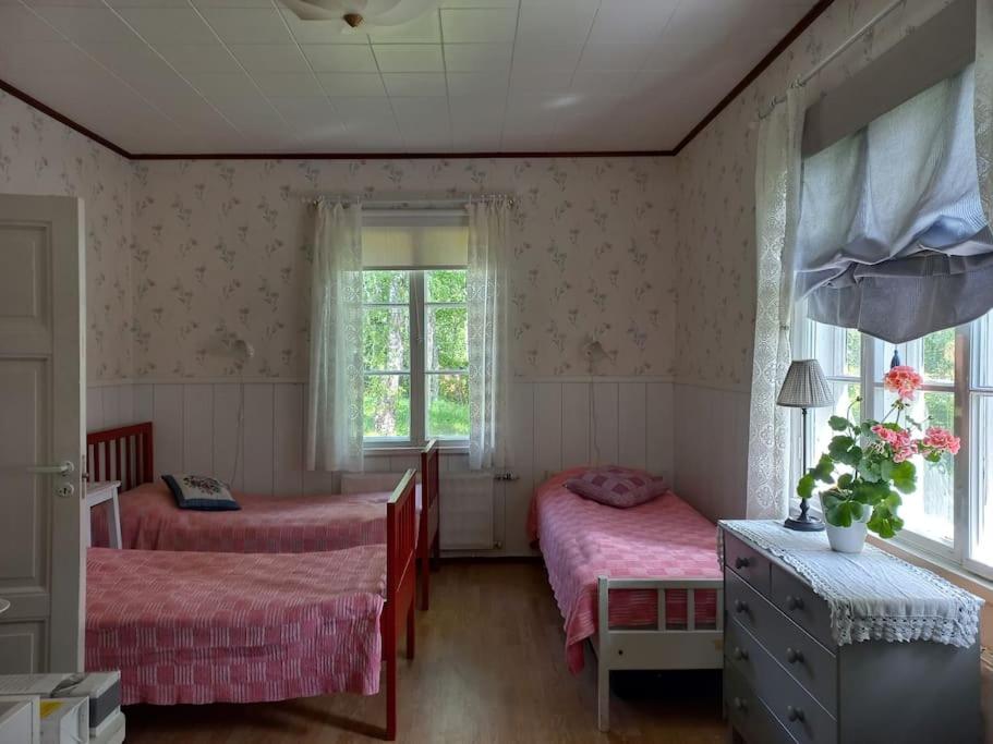 a bedroom with two beds and a window at Loma tai perhejuhlat Bobackan pihatorpassa in Hämeenlinna