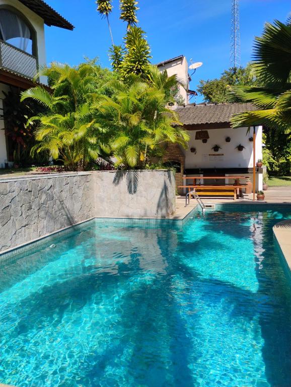 a swimming pool with blue water in front of a house at Flor da Mata in Pipa