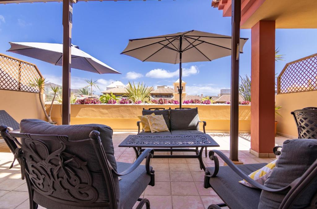 a patio with chairs and a table and an umbrella at Terrazas del Duque II Hideaway in Adeje