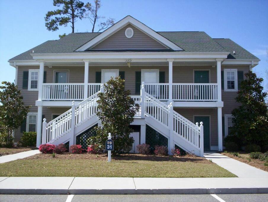 ein großes Haus mit einer weißen Veranda und einer Treppe in der Unterkunft Pawleys Island Retreat! in True Blue