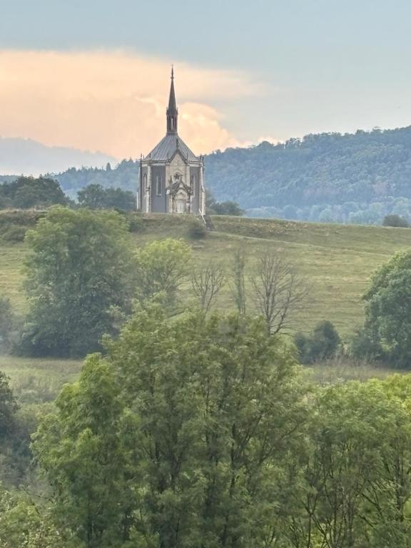 an old church on a hill with trees in the foreground at proche de la source in Ouhans