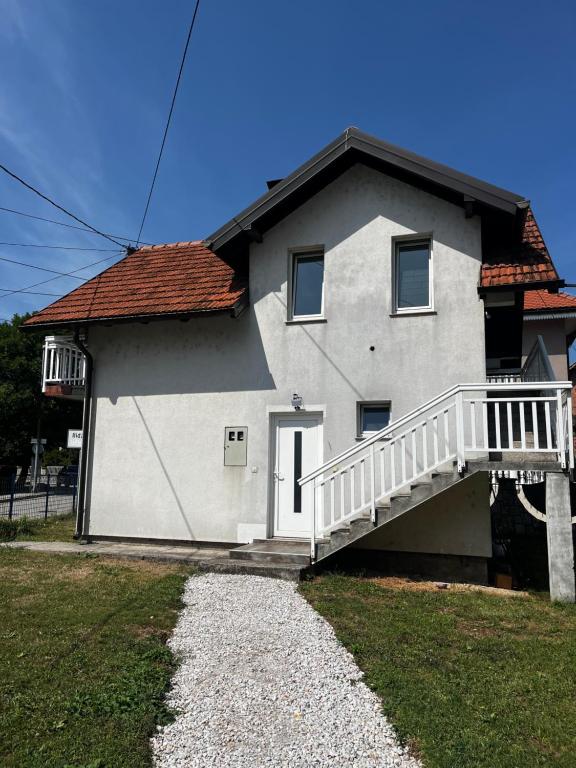 a white house with a white porch and a staircase at Apartment Aleja in Sarajevo