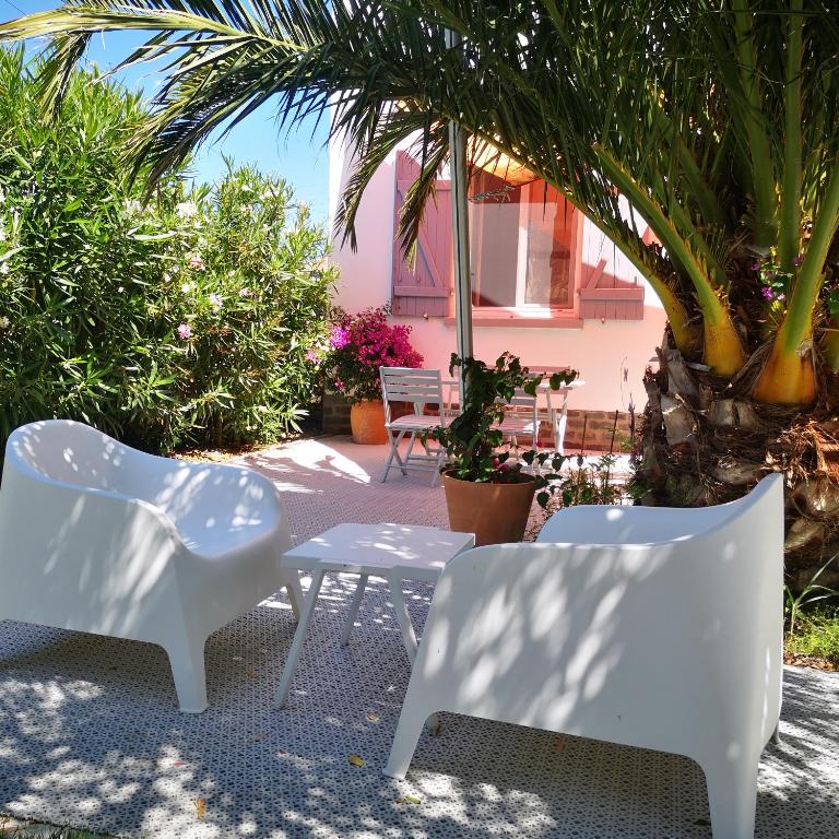 - 2 chaises blanches et une table sur la terrasse dans l'établissement Le chat bleu suite parentale chez l habitant cuisine partagée, à Beauvoir-sur-Mer