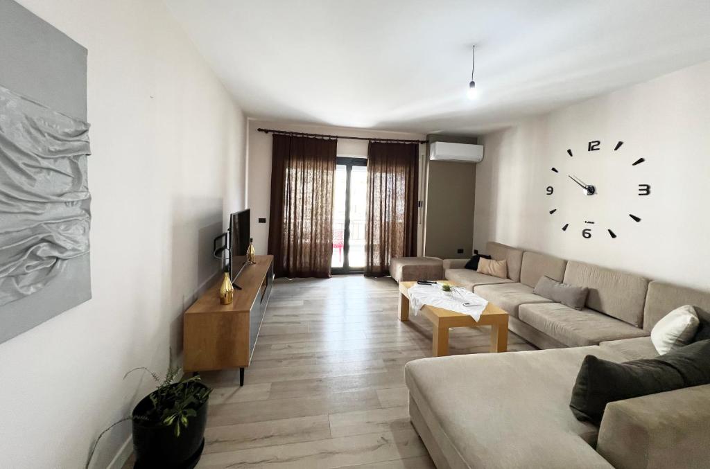 a living room with a couch and a clock on the wall at B2 Apartment in Tirana