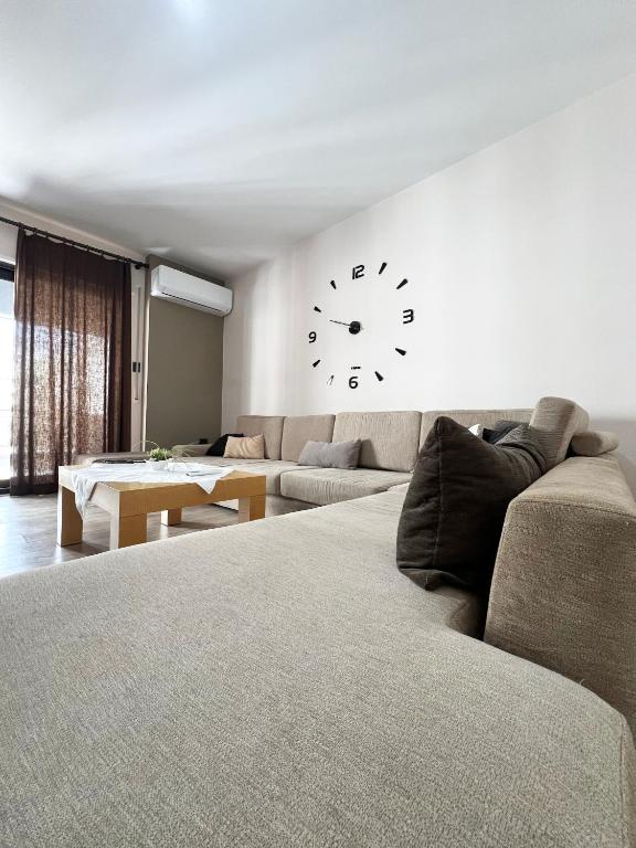 a living room with a couch and a clock on the wall at B2 Apartment in Tirana