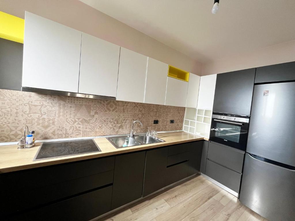 a kitchen with white cabinets and a sink and a refrigerator at B2 Apartment in Tirana