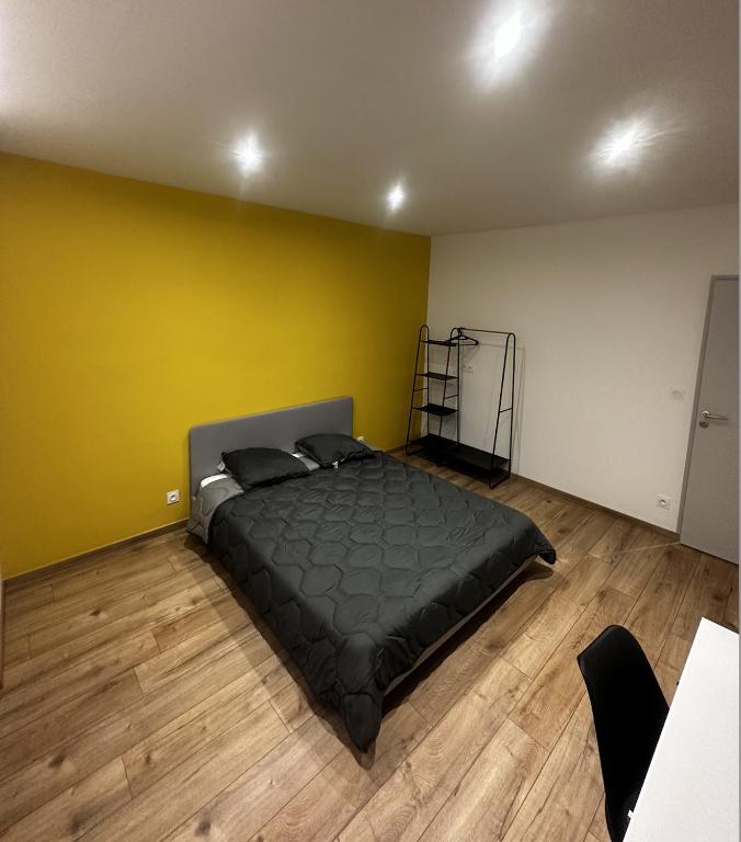 une chambre avec un lit avec un mur jaune dans l'établissement Chambre - Grenoble, Caserne de Bonne, à Grenoble