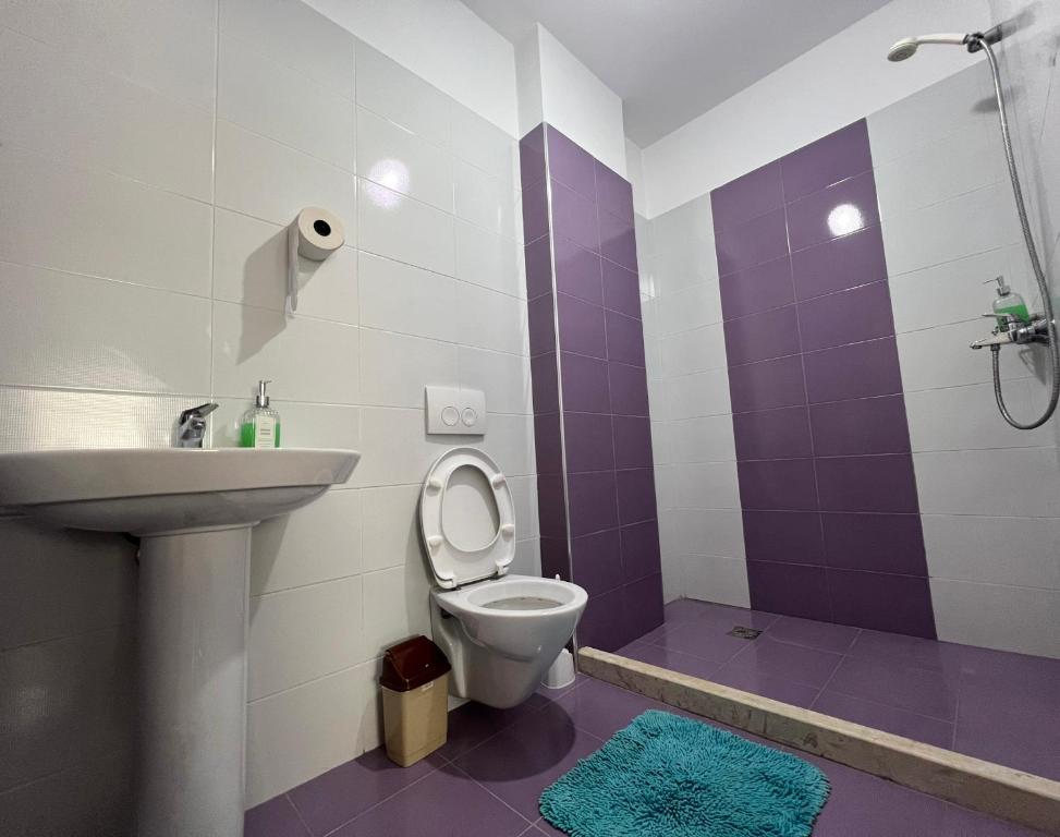 a purple and white bathroom with a toilet and a sink at B2 Apartment in Tirana