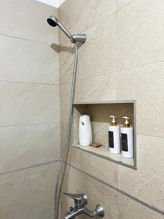 a shower with three bottles of soap on a shelf at B2 Apartment in Tirana