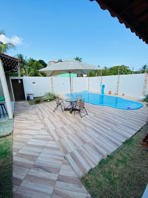 a patio with a table and an umbrella next to a pool at Casa da Barra99 in Francês