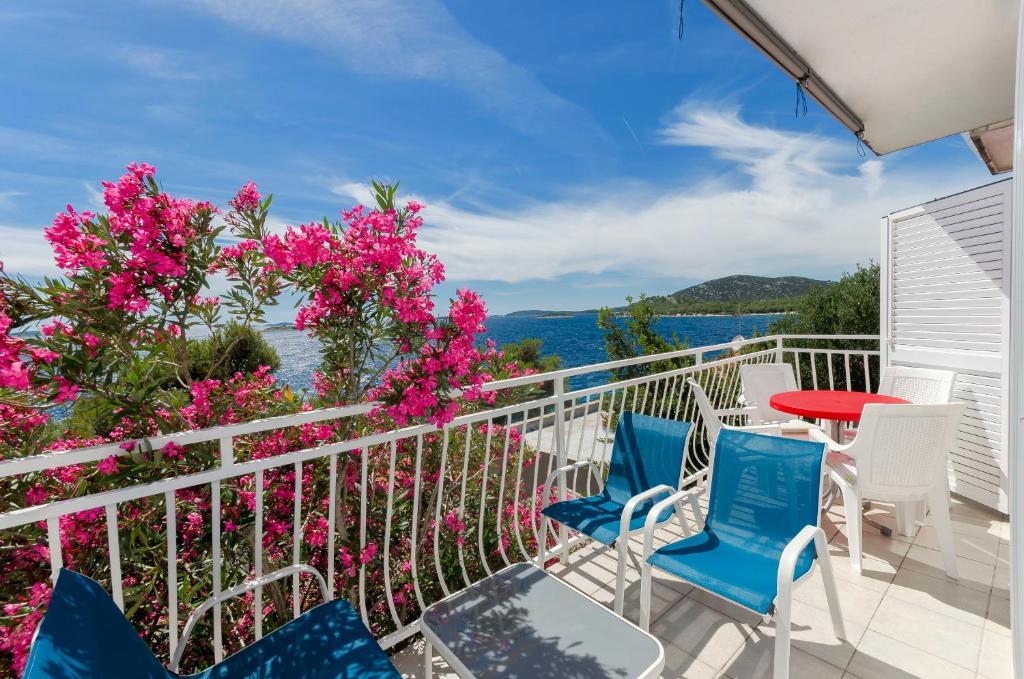a balcony with chairs and a table and pink flowers at Apartment Zamalin SeaView in Tribunj