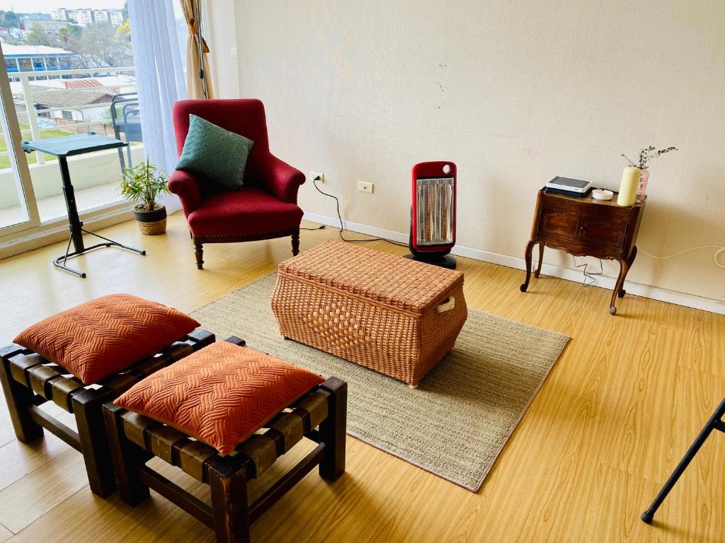 a living room with a red chair and a table at Departamento Central, con estacionamiento gratuito in Talca