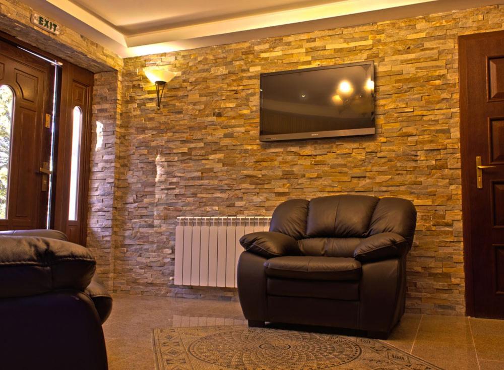 a living room with a chair and a television on a brick wall at Villa Katalina in Varna City