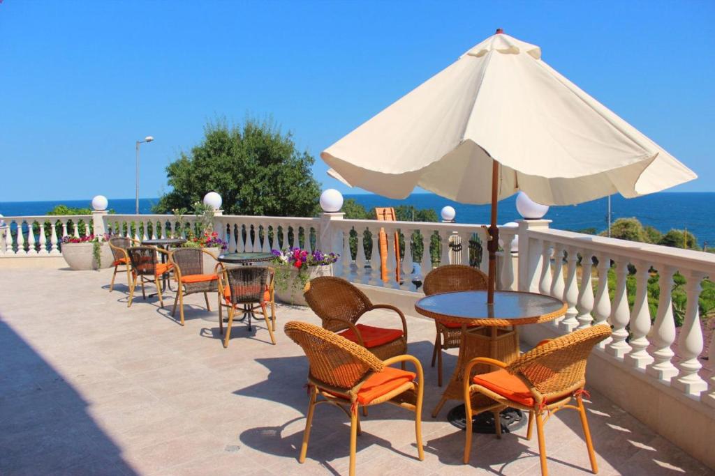 a patio with tables and chairs and an umbrella at Villa Katalina in Varna City