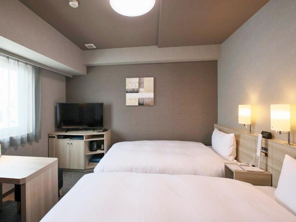 Postel nebo postele na pokoji v ubytování Hotel Route Inn HiratsukaEki Kitaguchi