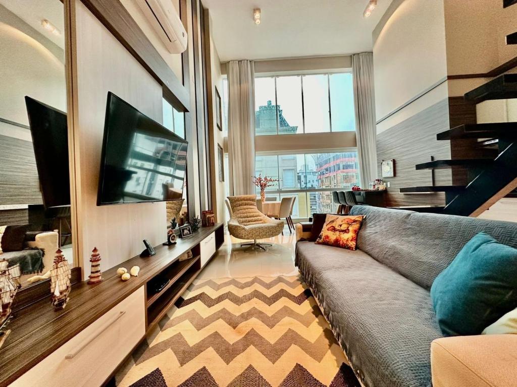 a living room with a couch and a tv at Apartamento Luxuoso de 2 Dormitórios in Capão da Canoa