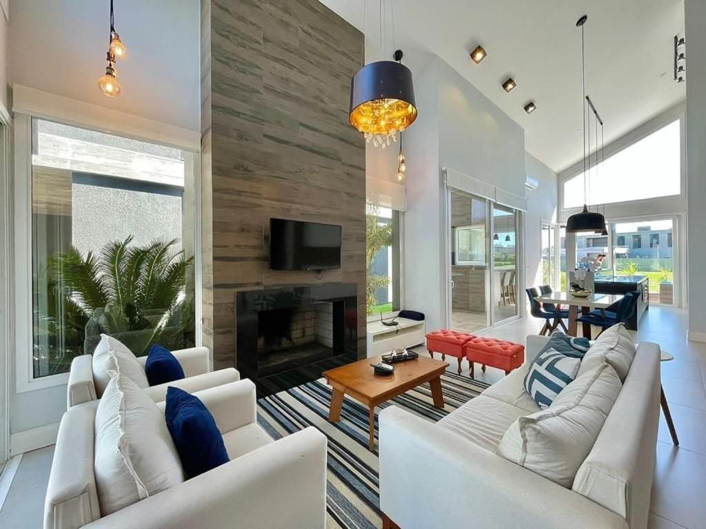 ein Wohnzimmer mit weißen Möbeln und einem Kamin in der Unterkunft Casa Luxuosa no Condomínio Ilhas Resort in Capão da Canoa