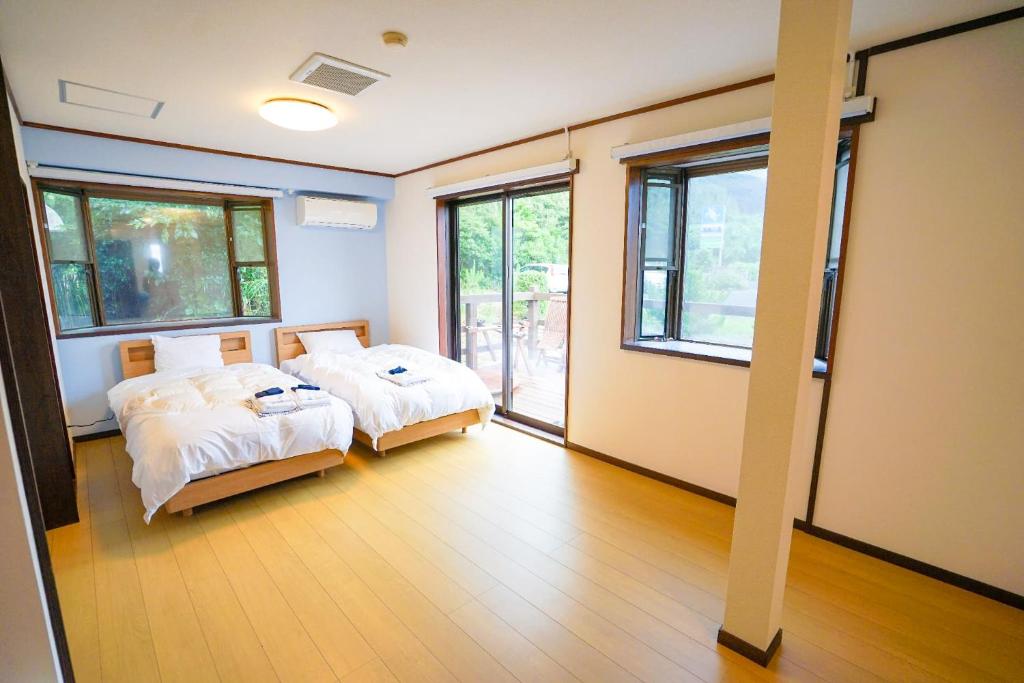 two beds in a room with two windows at Marine Blue Yakushima in Yakushima