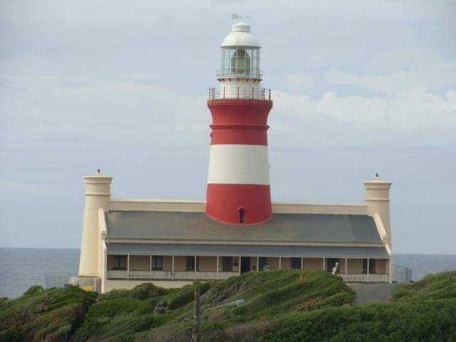 a red and white lighthouse sitting on top of a building at À La Mer - Selfcatering Unit in Agulhas