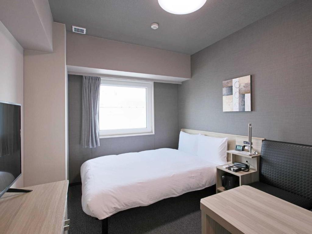 Postel nebo postele na pokoji v ubytování Hotel Route Inn HiratsukaEki Kitaguchi