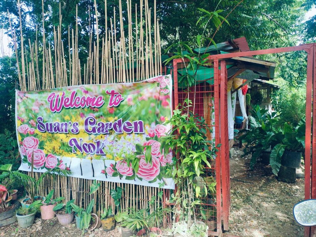 a sign in front of a garden with plants at Suan's Nook Guest House in Larena