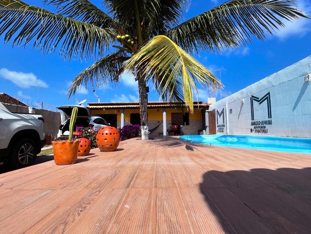 a palm tree in front of a house with a swimming pool at Dr House veraneio Abaís praia SERGIPE in Praia Da Caueira