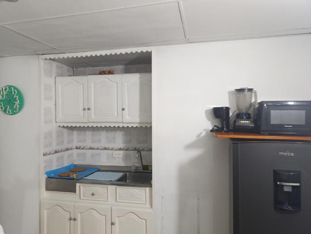 eine Küche mit weißen Schränken und einer Spüle und einer Mikrowelle in der Unterkunft Excelente vista al mar in Cartagena de Indias