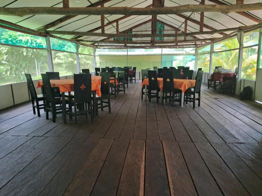 a dining room with tables and chairs on a wooden floor at Huasai tours & lodge in Iquitos