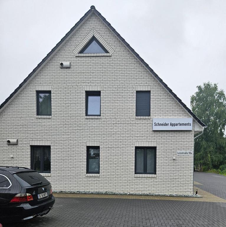 a white brick building with a black car parked in front at Schneider Apartments in Neustadt am Rübenberge